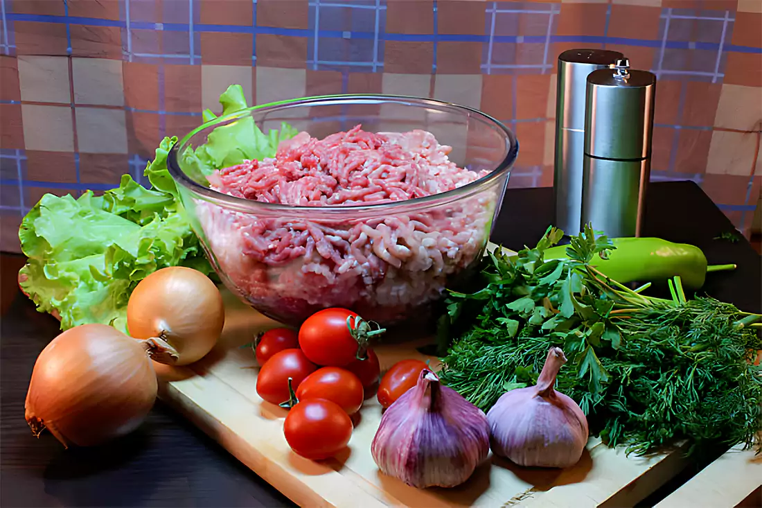 Various ingredients like ground beef, rice, onion, and spices on a kitchen counter, representing the preparation of Porcupine Meatballs.