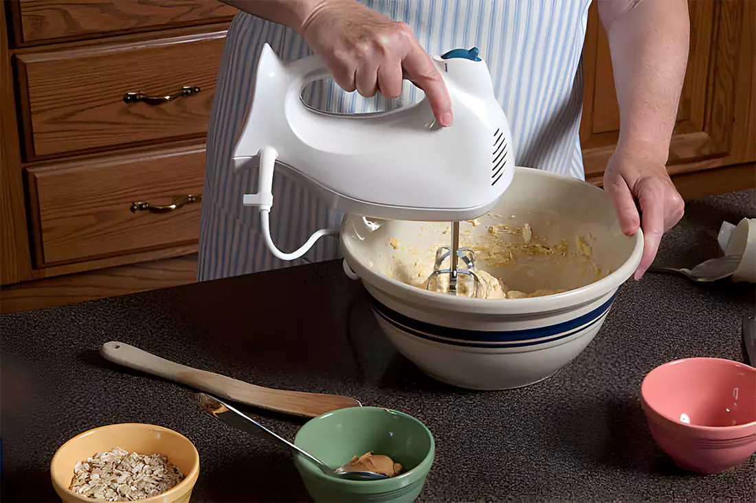 Hands shaping the peanut butter mixture into round balls, ready for dipping in chocolate