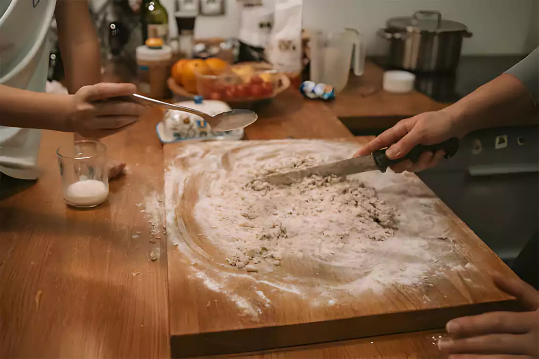 Hands kneading cinnamon bread dough on a kitchen surface